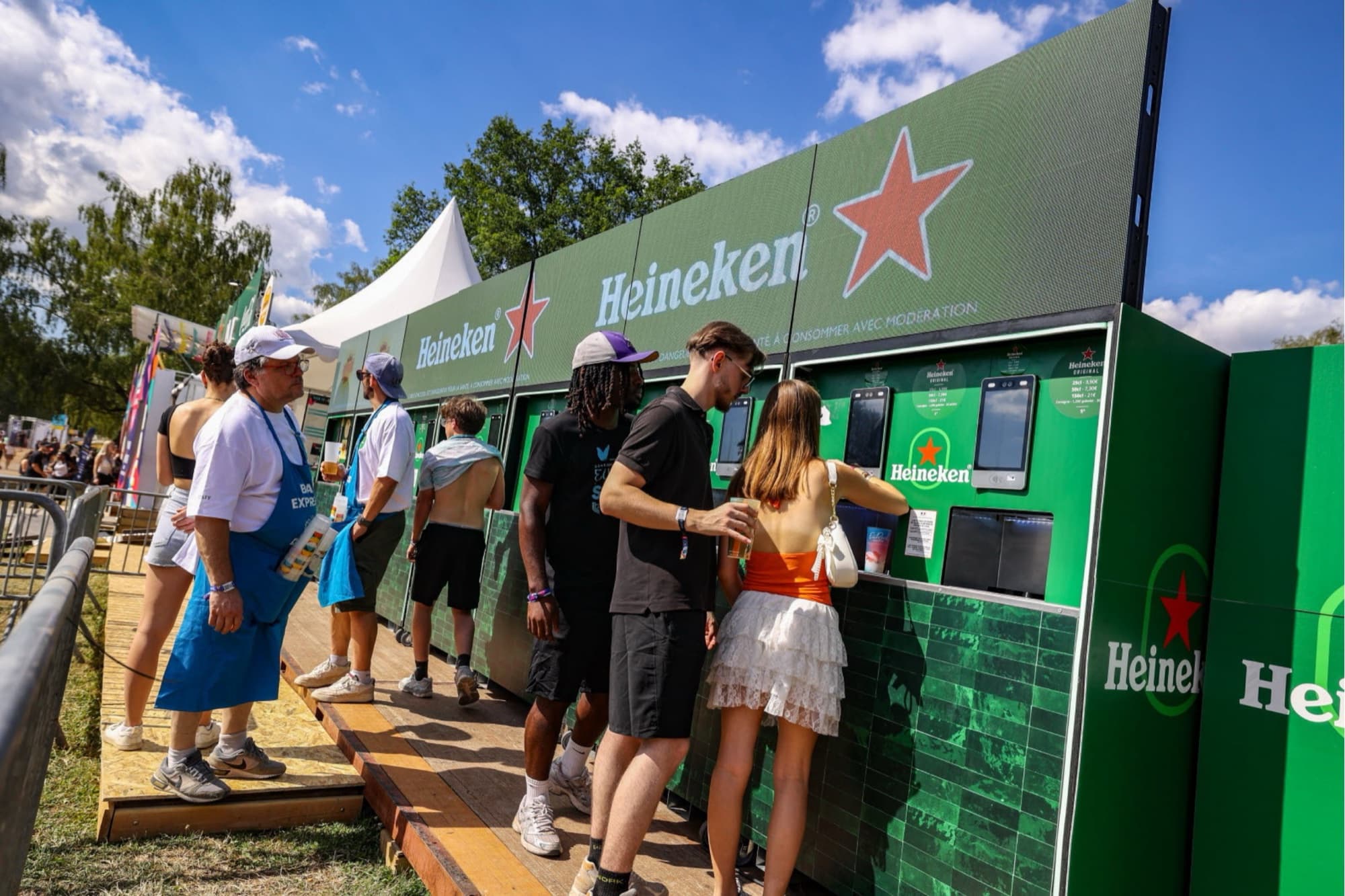 Batterie de machines de distribution en libre-service sur un festival, festivaliers en train de servir
