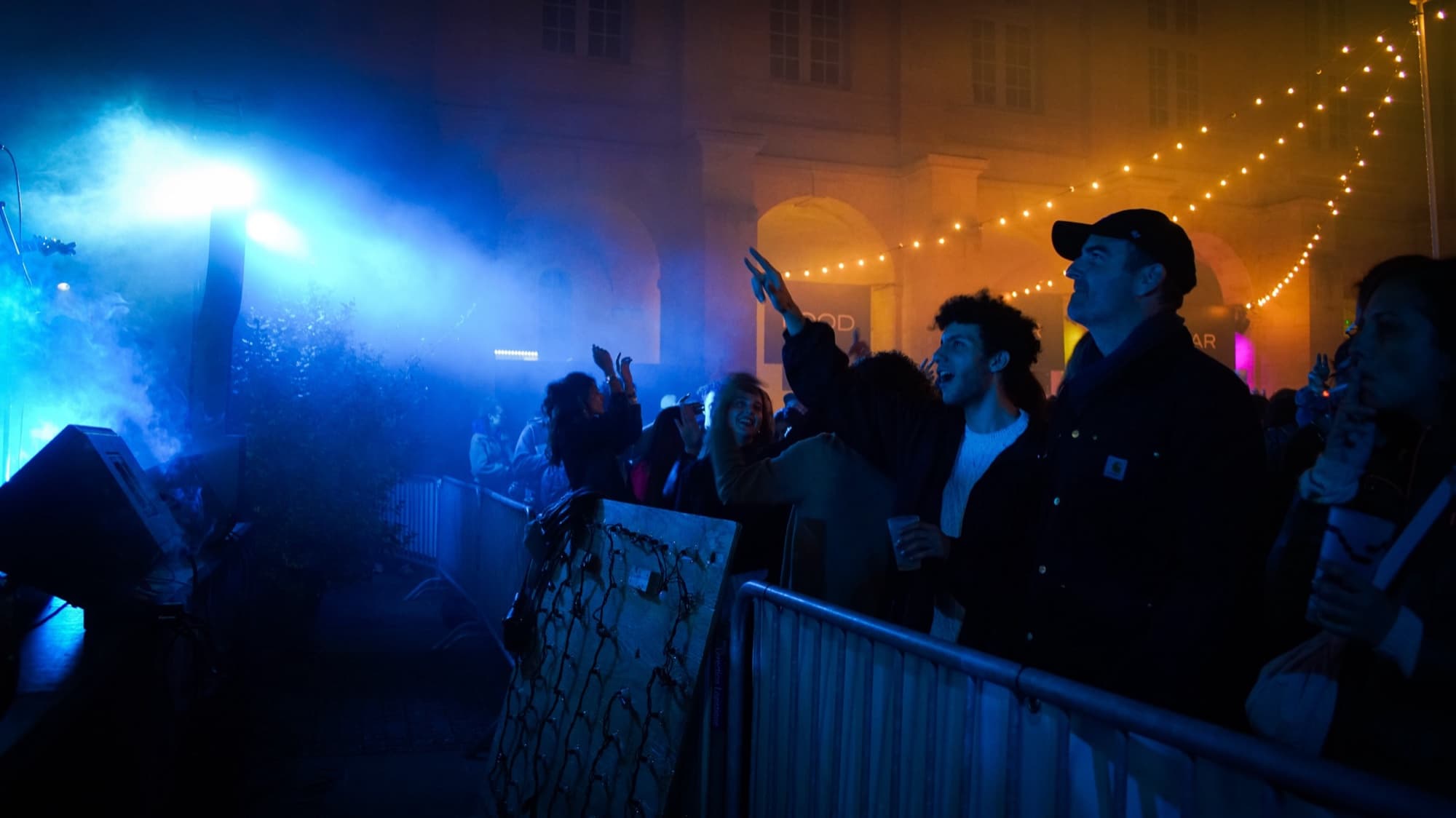 Public derrière les barrières devant une scène de plein air du FIFIB, fumée et lumière bleue