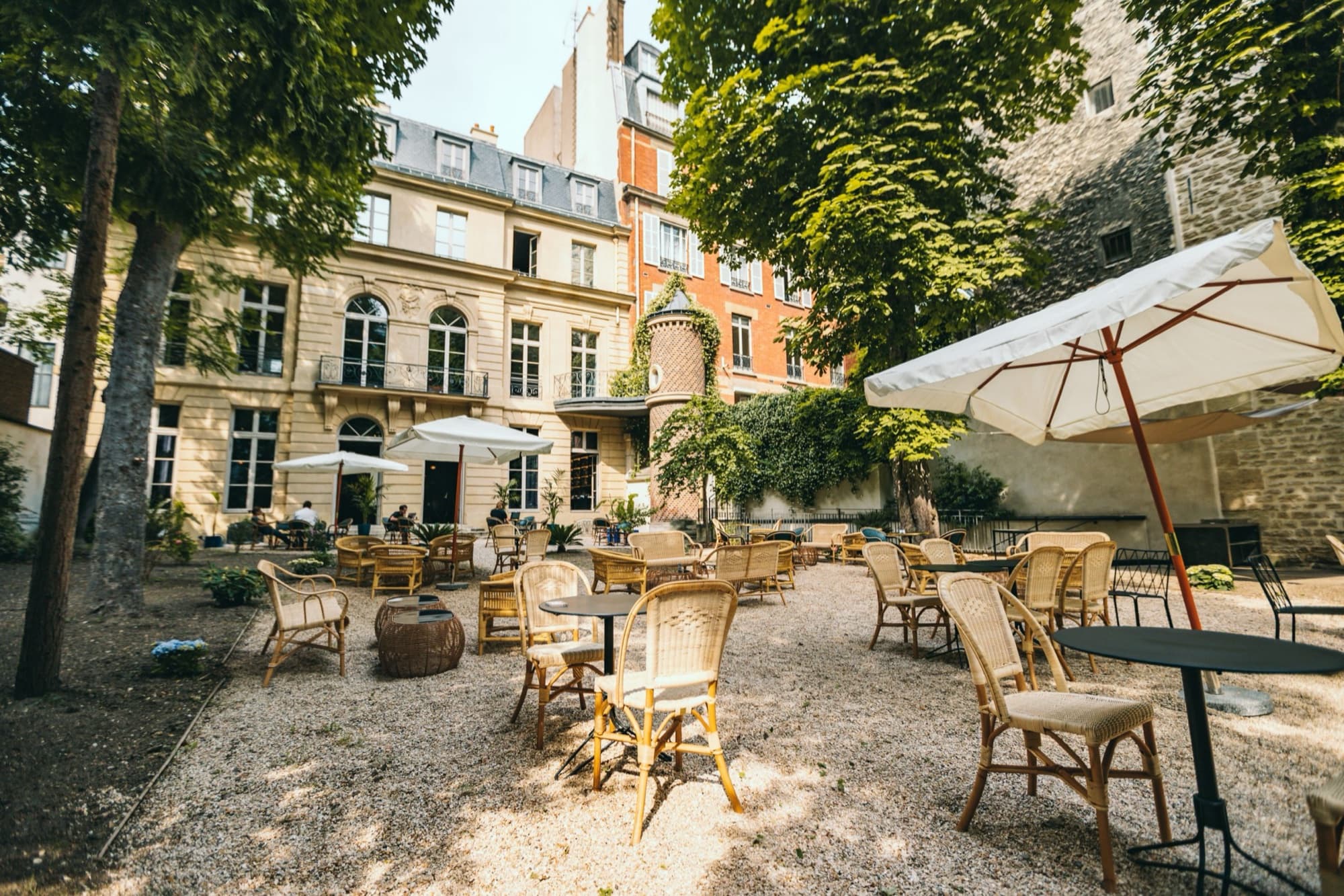 Cour-jardin de we are_ dressée en terrasse, tables et parasols