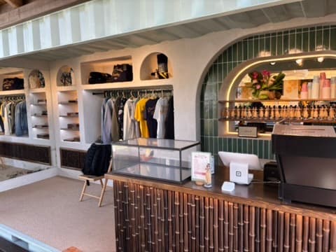 Corner boutique Breitling terminé : présentoirs, portants et machine à café derrière un bar en bambou