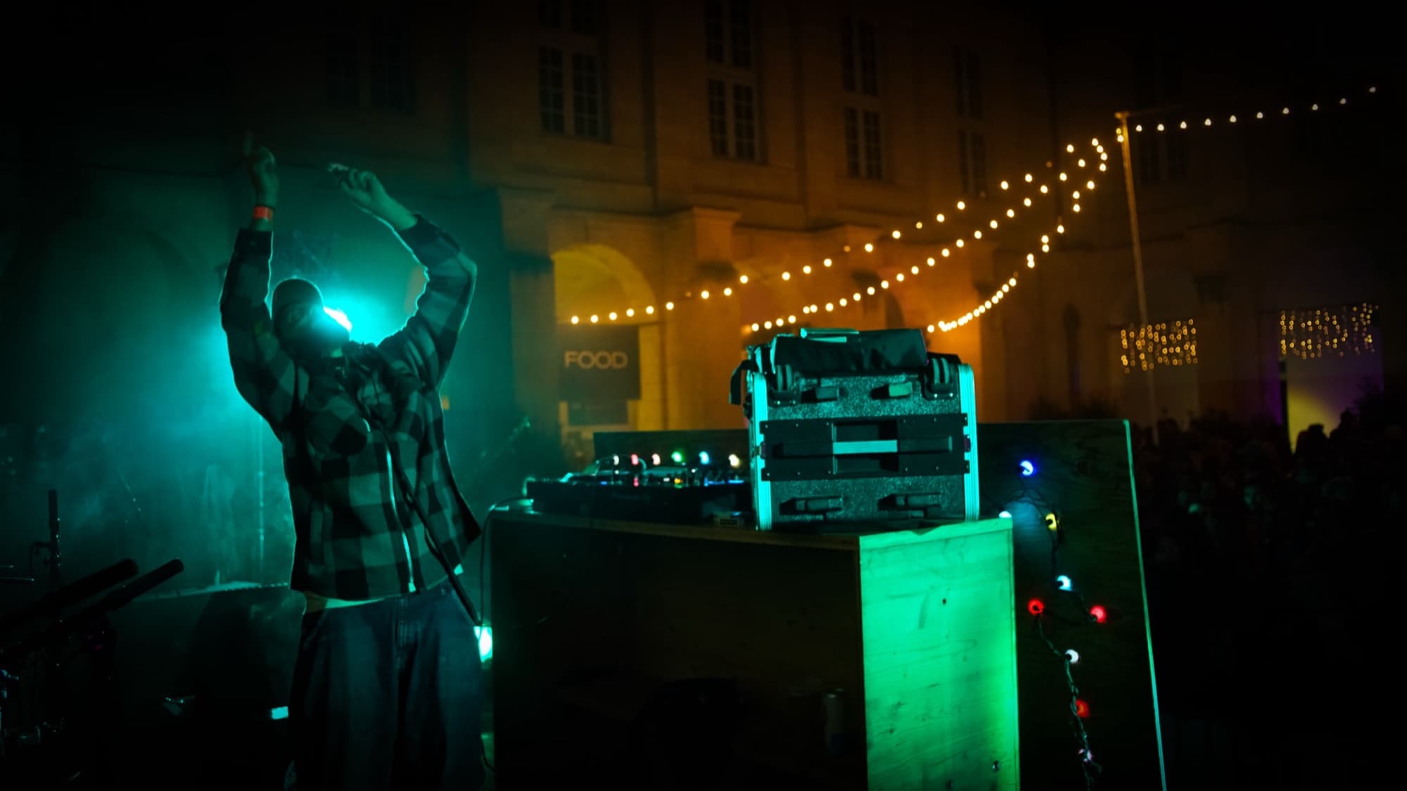 DJ en set sur la scène extérieure du Village du FIFIB, cour Mably, guirlandes lumineuses tendues